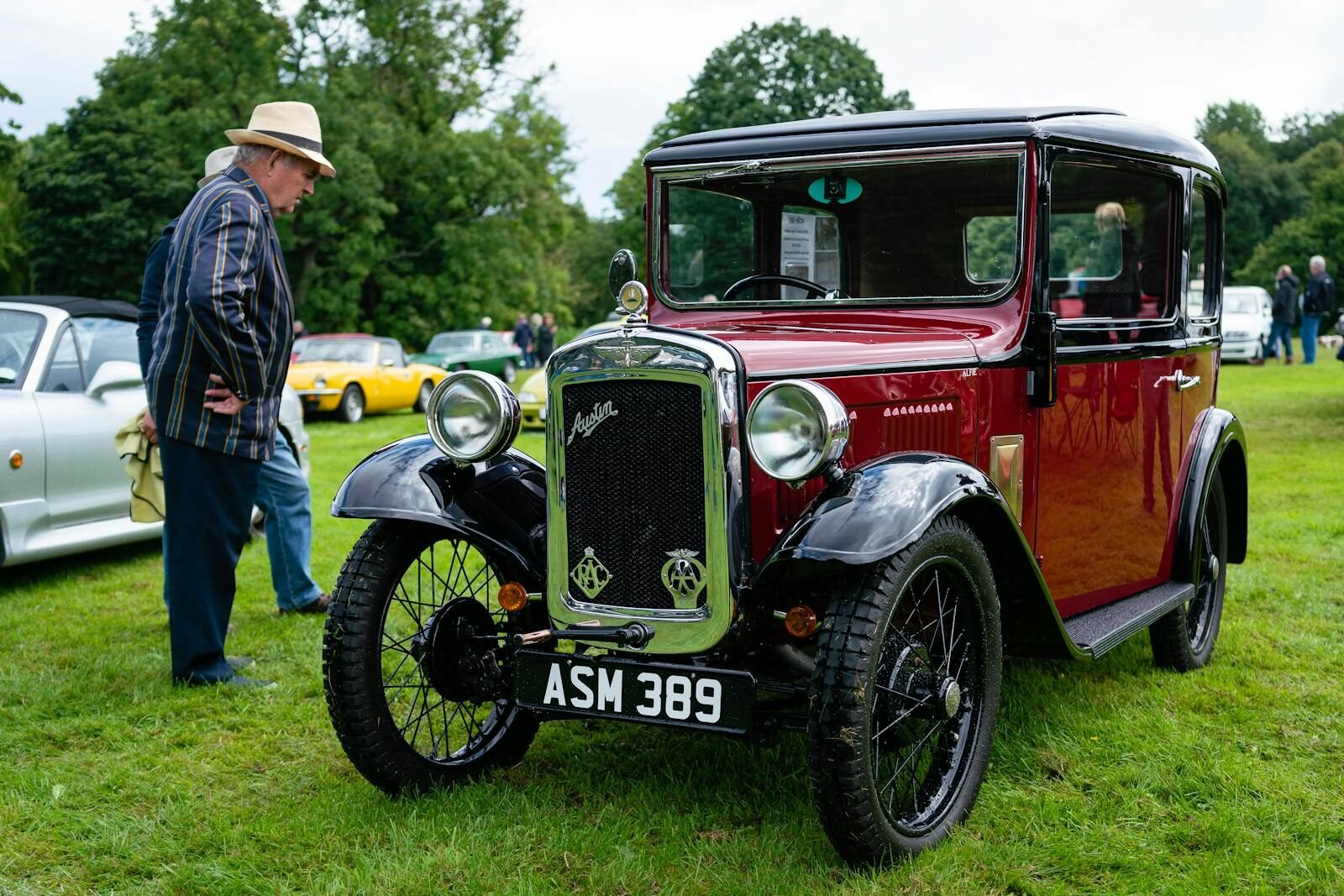 Classic Austin 7 car showcased at an outdoor car gathering with attendees around.